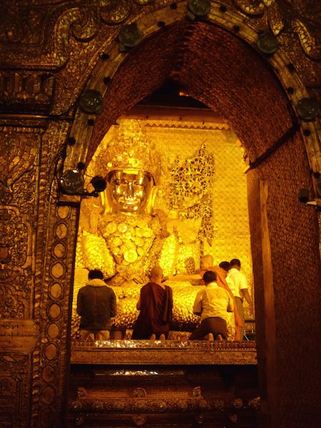 Monks and pilgrims applying their gold leaf offerings